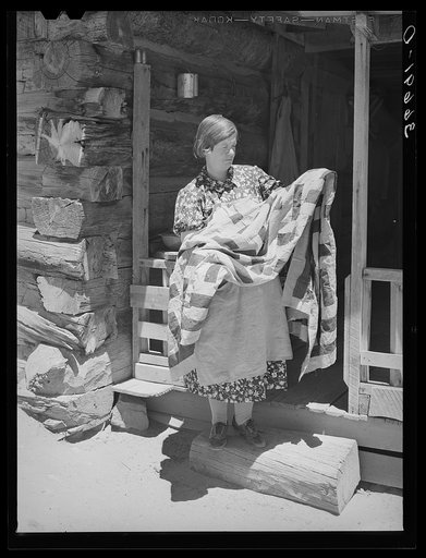 Mrs. Bill Stagg exhibiting a quilt made from tobacco sacks which she ripped up, dyed, and pierced. Nothing is wasted on these homesteading farms. Pie Town, New Mexico