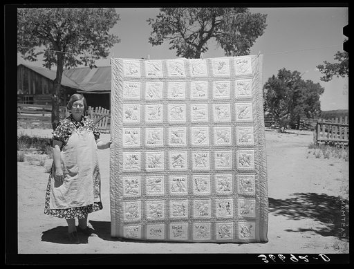 Mrs. Bill Stagg with state quilt she made. Mrs. Stagg helps her husband in the fields with plowing, planting, and weeding corn and harvesting beans, and quilts while she rests during the noon hour. Pie Town, New Mexico
