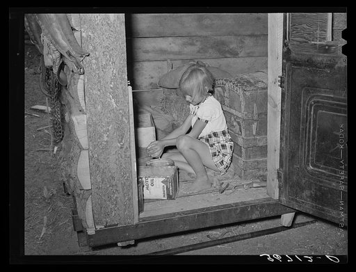 Daughter of homesteader getting chicken feed in slab shed. Trunk seen through the doorway was used to bring personal affects of the family west. Pie Town, New Mexico