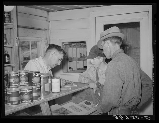 Mr. Keele, merchant and president of the Farm Bureau, making out bill for a farmer. Pie Town, New Mexico