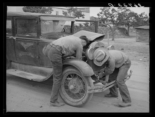 Garage owner and farmer working on a car. Pie Town, New Mexico. The young man who owns the filling station, blacksmith shop, and garage came out from Texas when he could not get work either on the farms or in the farming community towns there