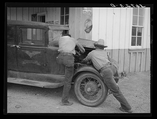Garage owner and farmer working on a car. Pie Town, New Mexico. The young man who owns the filling station, blacksmith shop, and garage came out from Texas when he could not get work either on the farms or in the farming community towns there