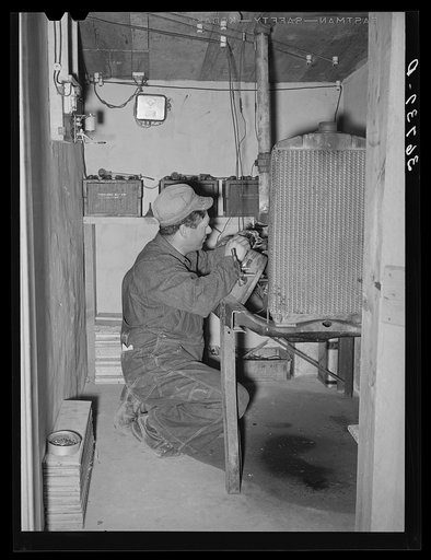 George Hutton, Jr., working on his homemade electric plant. Hutton took a correspondence course in electricity and has almost completely electrified all of his father's farm. Pie Town, New Mexico