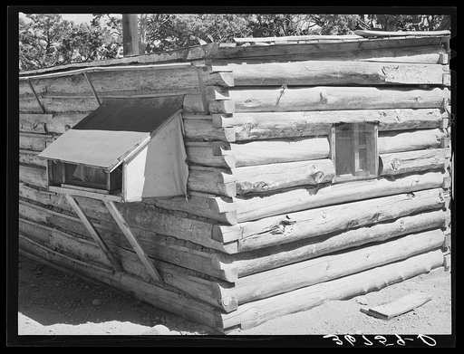 Corner of log house. Canvas-sided box at left is cooler. Milk, water, etc., are wrapped in wet cloths and the canvassed box allows a free circulation of air. Pie Town, New Mexico