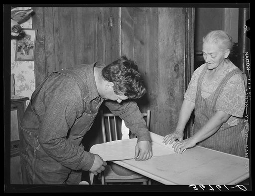 Mrs. George Hutton and her son measure off paper for the kitchen. Pie Town, New Mexico