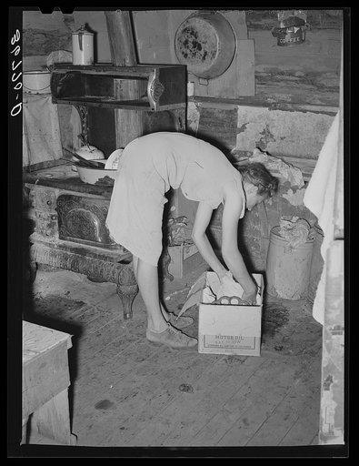 Untitled photo, possibly related to: Mrs. Faro Caudill packing up kitchen equipment for moving to new dugout nearer the well. Notice the pressure cooker. These homesteaders say that the pressure cooker should be put on the national flag for they think it's saving the farm folks for America. Pie Town