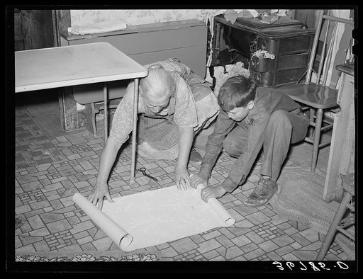 Mrs. Hutton and her grandson unrolling wallpaper for the kitchen. Pie Town, New Mexico