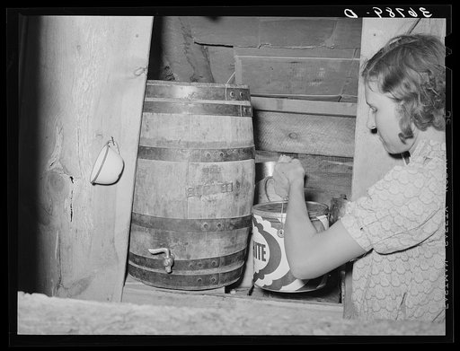 Mrs. Whinery placing bucket of milk in cooling room. Pie Town, New Mexico