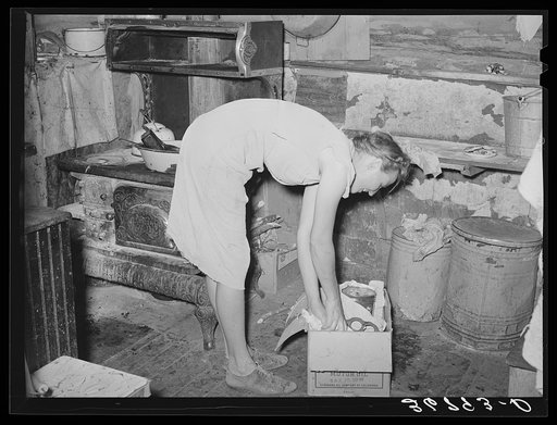 Untitled photo, possibly related to: Mrs. Faro Caudill packing up kitchen equipment for moving to new dugout nearer the well. Notice the pressure cooker. These homesteaders say that the pressure cooker should be put on the national flag for they think it's saving the farm folks for America. Pie Town