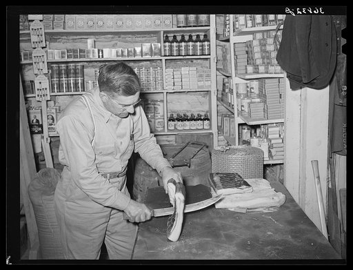 Mr. Keele slicing bacon in the general store at Pie Town, New Mexico