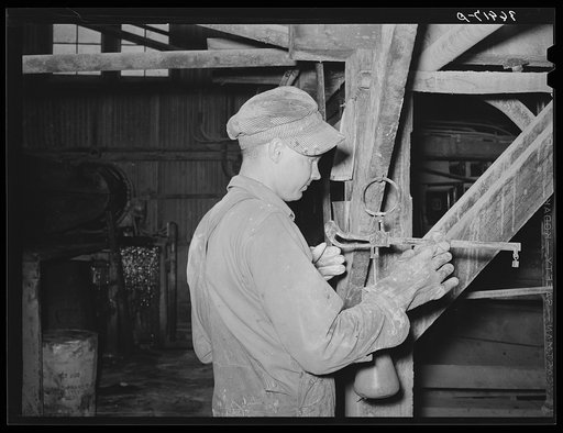 Workman weighing sample of gold ore and cyanide solution to determine if proper concentration of liquid is being maintained. Mogollon, New Mexico