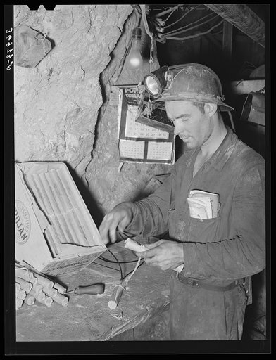 Miner inserting fuse into stick of dynamite. Mogollon, New Mexico