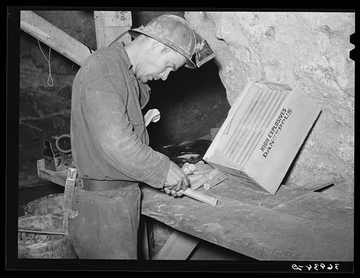 Miner inserting fuse into stick of dynamite. Mogollon, New Mexico