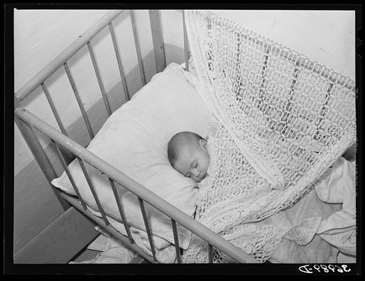 Spanish-American baby in its crib. Chamisal, New Mexico
