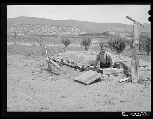 Spanish-American farmer coming out of fruit storage cellar. Chamisal, New Mexico