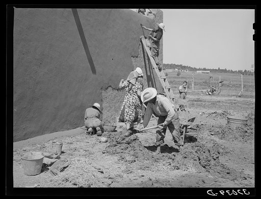 Untitled photo, possibly related to: Mixing plaster for house, Chamisal, New Mexico. Occasionally a man helps with the hard work of mixing plaster but the women never allow the men to help with the actual plastering of the house