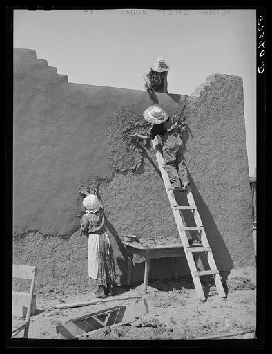 Once a year the women in the Spanish-American families replaster the adobe houses. Neighboring women are hired to help with the work. Chamisal, New Mexico