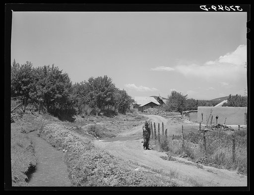 Untitled photo, possibly related to: Irrigation ditch flows across road at entrance to Chamisal, New Mexico