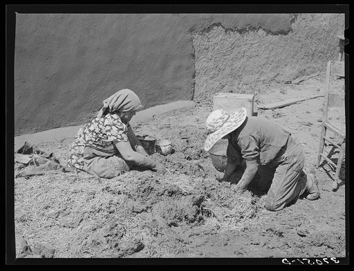 Mixing straw with mud to make the plaster which is used to replaster the houses once a year. Chamisal, New Mexico