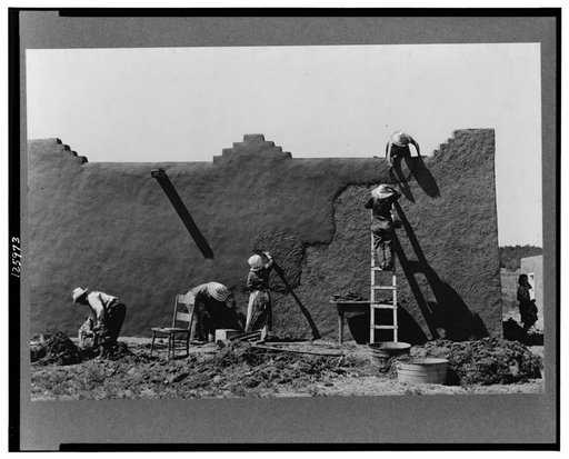 Spanish-American women replastering an adobe house. This is done once a year. Chamisal, New Mexico