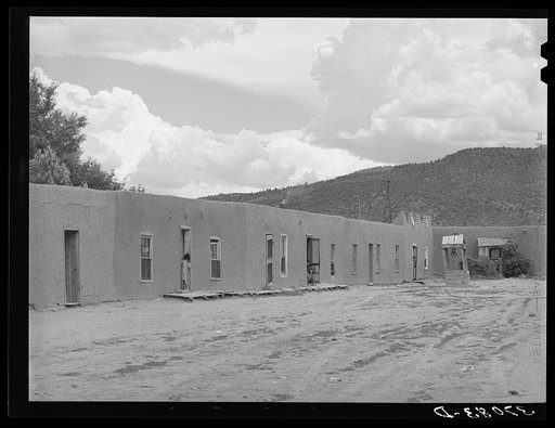 Row of adobe dwellings in Costilla, New Mexico. Well in square supplies several families with water