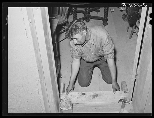 Spanish-American farmer fitting floor step into place. Amalia, New Mexico.  The Spanish-Americans are adept in carpentry and cabinet work