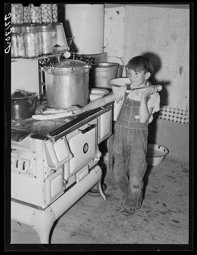 Spanish-American boy eating sweet corn which he has roasted on top of hot stove. Chamisal, New Mexico