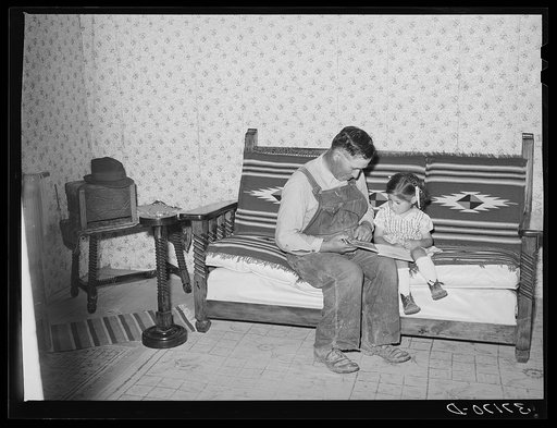 Spanish-American farmer and his daughter seated on couch which his son made at school workshop in Albuquerque. Chamisal, New Mexico