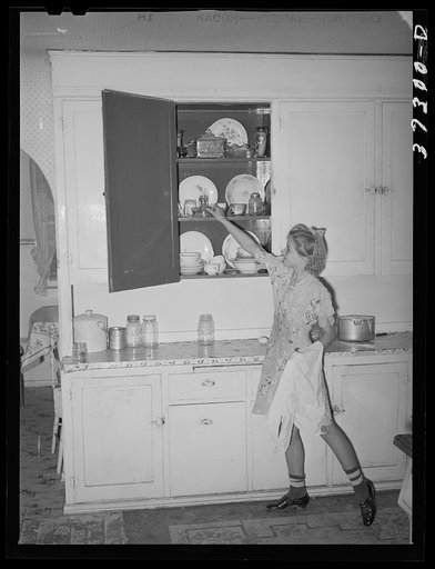Untitled photo, possibly related to: Daughter of Morman [i.e. Mormon] farmer putting away dishes in kitchen cabinet. Box Elder County, Utah