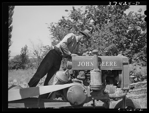 Farmer looking at the tank of tractor to see if it needs fuel. Box Elder County, Utah