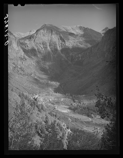 Mountain valley near Telluride showing gold mill and Bridal Veil Falls and road winding around mountain up to the mine. San Miquel County, Colorado