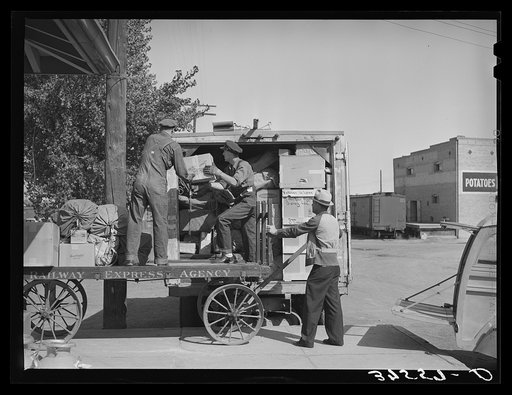 Loading express packages into D. & R.G.W. truck which takes them to points on the narrow gauge railroad where passengers and express service is not otherwise available. Montrose, Colorado