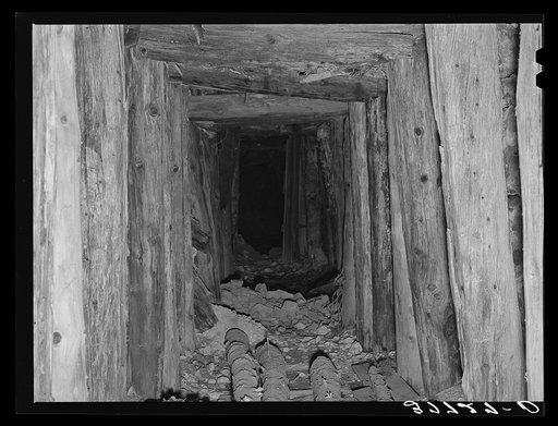 Timbered tunnel leading into mine. San Juan County, Colorado. Barren mountain sides attest to the amounts of timber which was used in construction of such tunnels as this