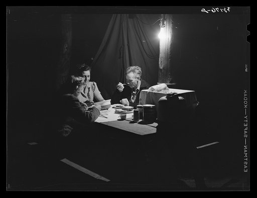 Carpenter, his wife and daughter eating supper in front of their tent-home. Mission Valley, California, about three miles from San Diego. Refer to caption 38175-D