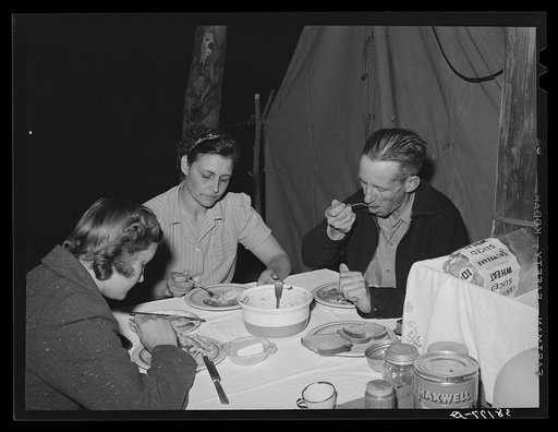 Carpenter, his wife and daughter eating supper in front of their tent-home. Mission Valley, California, about three miles from San Diego. See caption 38175-D