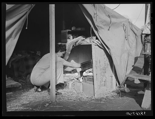 Carpenter's wife taking things out of improvised closet in her tent-home. Mission Valley, California, about three miles from San Diego
