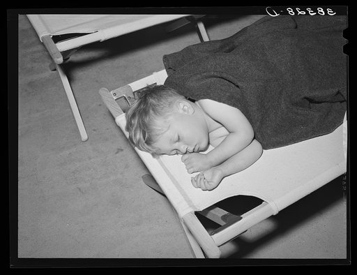 Boy asleep in community building of the Yuba City farm workers' camp. Yuba City, California