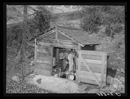Fruit farmer in springhouse. Placer County, California. Notice the electric pump which makes possible running water in the house