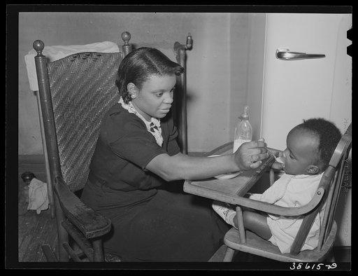 Wife of railroad worker feeding her baby. Chicago, Illinois