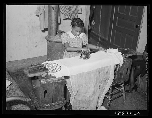 Little girl ironing. Family is on relief. Chicago, Illinois