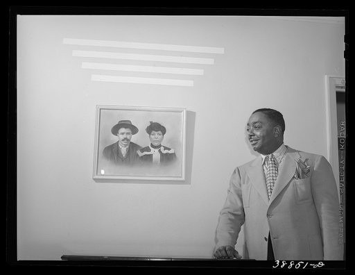 Prosperous Chicagoan posed by photograph of his parents. Chicago, Illinois