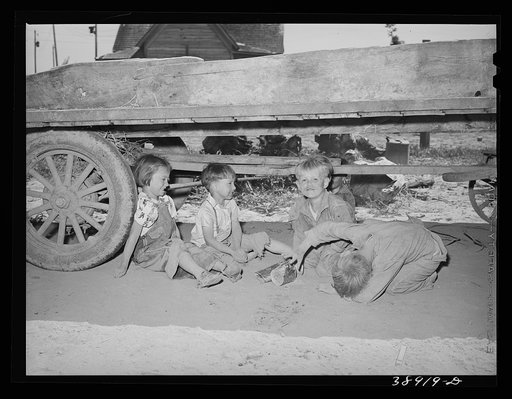 Children playing under wagon at the Schroder farm, FSA (Farm Security Administration) rehabilitation borrowers living on Dead Ox Flat. Vale-Owyhee irrigation project, Malheur County, Oregon