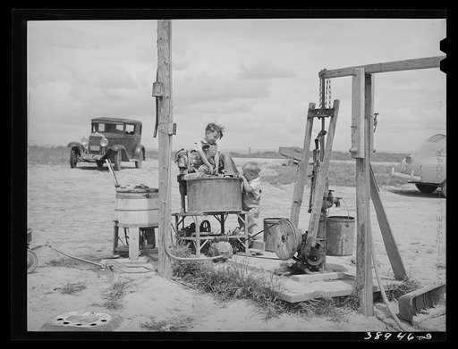 Children of Ray Halstead playing around the well. An electric motor is arranged so that it pumps water and supplies power for the washing machine. He is a FSA (Farm Security Administration) rehabilitation borrower. Dead Ox Flat, Malheur County, Oregon