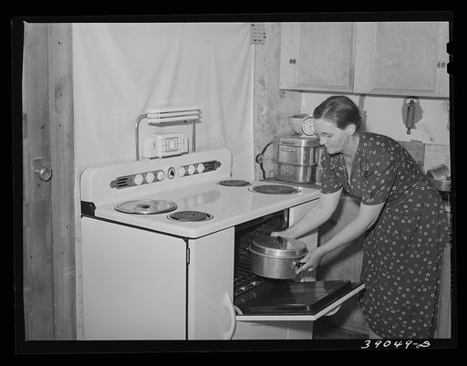 Wife of Mr. E.E. Botner, FSA (Farm Security Administration) rehabilitation borrower, putting roasting pan into electric stove. Nyssa Heights, Malheur County, Oregon