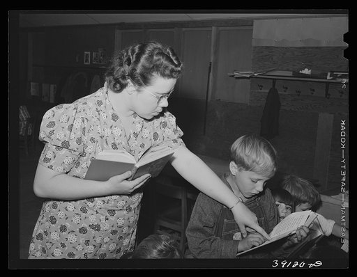 Teacher helps pupil with his reading, FSA (Farm Security Administration) camp for farm workers. Caldwell, Idaho. School is held at the camp because of lack of room in city schools