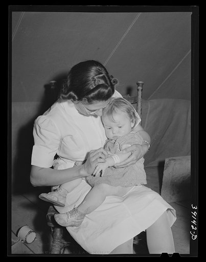 Nurse looks at cut on baby's arm at the FSA (Farm Security Administration) migratory labor camp mobile unit. Wilder, Idaho. The nurse not only is in attendance at the trailer clinic, but makes her regular rounds of calls to the tents