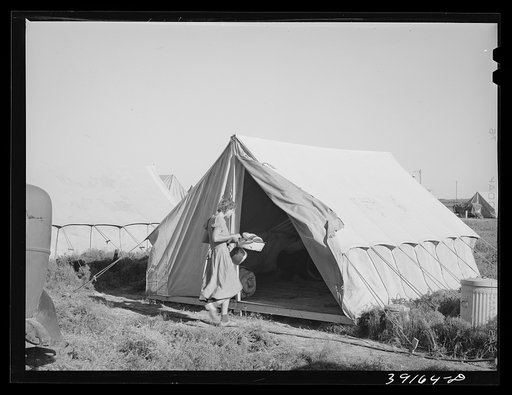 Farm worker's wife taking household equipment into the tent in which she will stay at the FSA (Farm Security Administration) migratory labor camp mobile unit. Wilder, Idaho