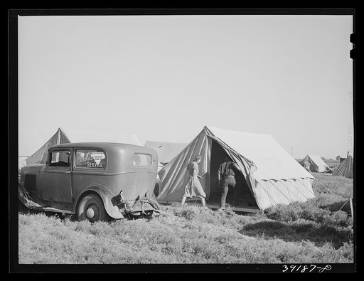 Farm workers unloading their car and moving into tent in which they will live at the FSA (Farm Security Administration) migratory labor camp mobile unit. Wilder, Idaho. Tents are floored. The fact that sanitary facilities are available, hot and cold running water for bathing and laundry work, shower