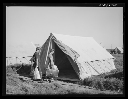 Farm workers unloading their car and moving into tent in which they will live at the FSA (Farm Security Administration) migratory labor camp mobile unit. Wilder, Idaho. Tents are floored. The fact that sanitary facilities are available, hot and cold running water for bathing and laundry work, shower
