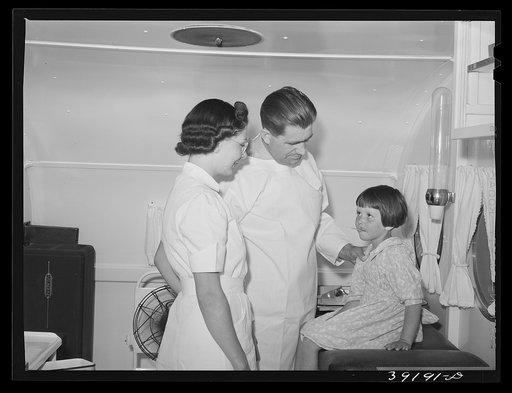 Doctor and nurse with little girl in trailer-clinic at the FSA (Farm Security Administration) migratory labor camp mobile unit. Wilder, Idaho
